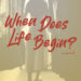 Book cover featuring woman standing on a stage with text: When Does Life Begin?