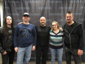 Photo of three members of Disturbed with two people.