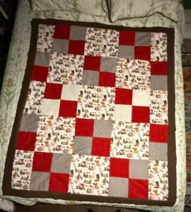A brown, red, and dog-patterned quilt top.