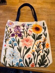 A floral patterned tote bag with navy handles.