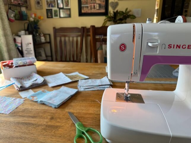 A Singer Simple sewing machine on a table with quilting material.